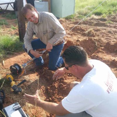 Leonard Smith (top) and Travis Ridgeway (left), install a guy wire to an anchor in the ground to support the tower.
